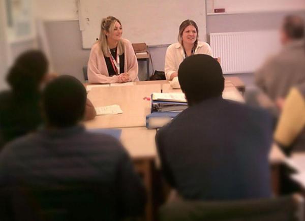 people sit around a desk in a classroom facing two BSU academics