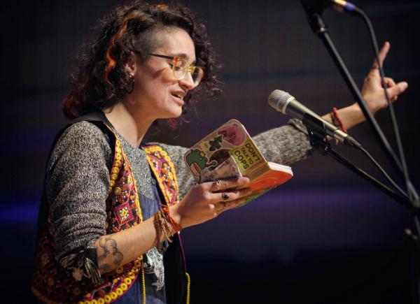 A woman on a mic, reading a poem